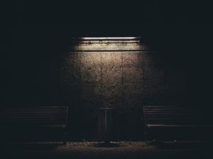 Brown painted wall with two benches and dim light above